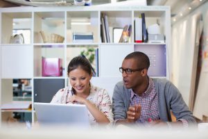Man and women using laptop in office.